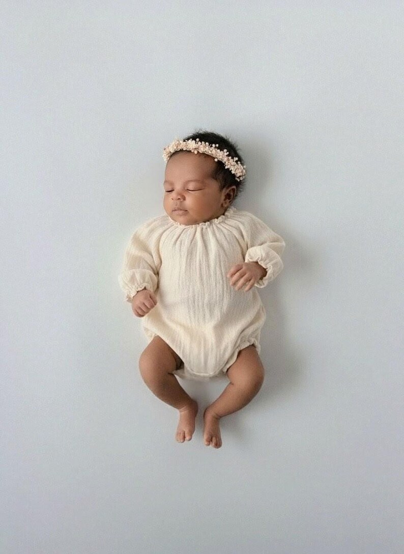 Sleeping infant dressed in the ethereal Lylou newborn romper with a delicate floral headband. The premium crinkled cotton introduces 3D depth, serving as a breathtaking studio newborn photo prop.