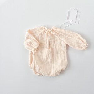 Full back profile of the vanilla Lylou newborn outfit girl flat lay. The balloon-style silhouette and rich texture harmonize beautifully with wooden studio floors for fine art newborn photography.