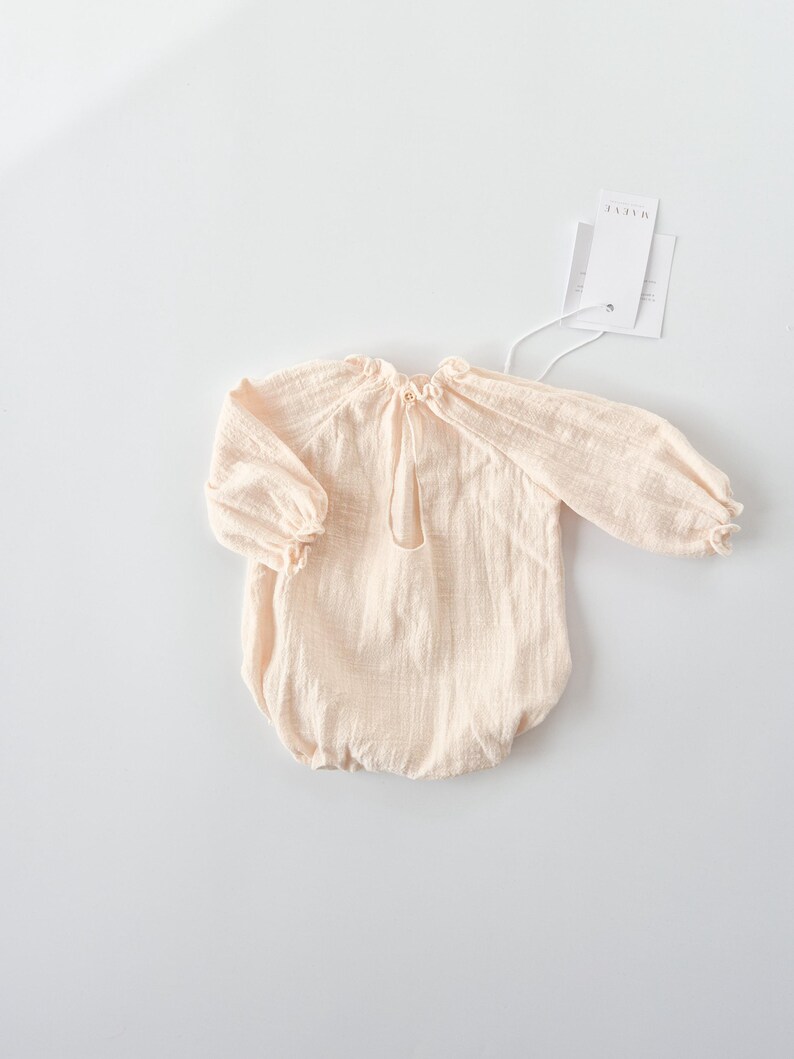Full back profile of the vanilla Lylou newborn outfit girl flat lay. The balloon-style silhouette and rich texture harmonize beautifully with wooden studio floors for fine art newborn photography.
