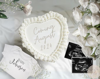 Könnte beinhalten: Ein weißer herzförmiger Kuchen mit den Worten "Coming August 2024" darauf. Es gibt einen weißen Strampler mit den Worten "Baby Johnson" darauf und zwei Schwarzweiß-Ultraschallbilder.