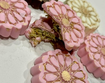 May include: Assortment of pink, white, and brown cookies with gold detailing. The cookies are decorated with a floral design.