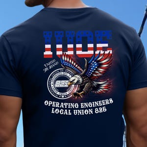 May include: A navy blue t-shirt featuring a graphic on the back with the letters IUOE in a red, white, and blue flag pattern. It includes a bald eagle, the text United We Stand, and a circular seal for Operating Engineers Local Union 825.