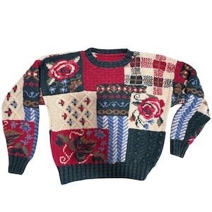 Könnte beinhalten: Ein Patchwork-Pullover mit Rundhalsausschnitt und langen Ärmeln. Das Design umfasst florale, geometrische und Zopfmuster. Die Farben sind Rot, Grün, Creme und Blau. Der Pullover ist eine Mischung aus verschiedenen Mustern.