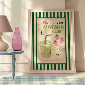 May include: A framed poster with a green and white striped border, displaying the text "the MATCHA CLUB Est. 2025". The poster features a matcha drink illustration, strawberries, and the text "FOR THE BEST RESULT MIX BEFORE DRINKING, AND THEN ENJOY YOUR MATCHAIN".
