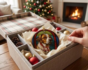 May include: A round ceramic Christmas ornament featuring a stained-glass style illustration of a brown and white dog. The dog is centred within a red and blue frame. The text "Dogs Name" is written in red script across the dog's chest area.