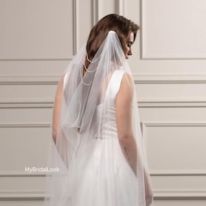 Velo de novia suave y drapeado con cadenas de perlas