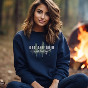 May include: A navy blue sweatshirt with a green and white graphic of trees and the text "Off the Grid and loving it".