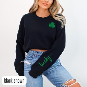 May include: Black cropped sweatshirt with a green shamrock and the word "lucky" written in green on the sleeve.
