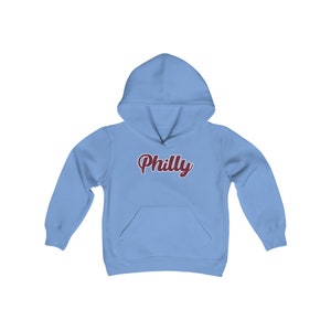 Könnte beinhalten: Ein hellblauer Kapuzenpullover mit einem burgunderfarbenen "Philly"-Aufdruck auf der Vorderseite.