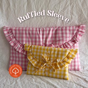 Op de afbeelding: Twee pouches met gerimpelde mouwen in roze en gele gingham stof. De roze pouch is groter, met een eenvoudige sluiting. De gele pouch is kleiner, met een strik detail. De tekst "Ruffled Sleeve" staat bovenaan.
