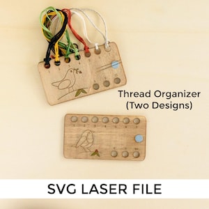 Puede incluir: Dos organizadores de hilo de madera con diseños de pájaros. Cada organizador tiene diez agujeros numerados para sujetar el hilo. El organizador superior tiene un pájaro con una rama de bayas en el pico. El organizador inferior tiene un pájaro con una sola baya. Ambos organizadores tienen un punto azul en el décimo agujero.