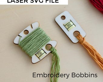 May include: Wooden embroidery bobbins with green and orange thread. One bobbin is wrapped with green thread and labeled with the number 730. Another bobbin is labeled with the number 988. The text "LASER SVG FILE" and "Embroidery Bobbins" are also visible.