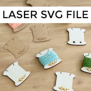 May include: A set of six wooden thread spool holders with a simple leaf design. The holders are in various shades of brown and white. The text "LASER SVG FILE" is at the top of the image.