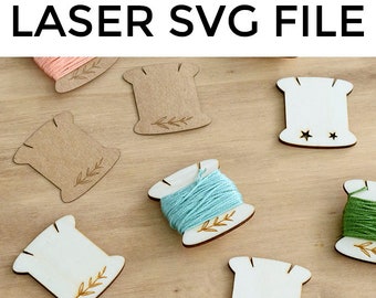 May include: A set of six wooden thread spool holders with a simple leaf design. The holders are in various shades of brown and white. The text "LASER SVG FILE" is at the top of the image.