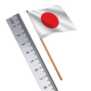 May include: A white flag with a red circle in the center, attached to a wooden stick. A ruler with centimeter markings is in the background.