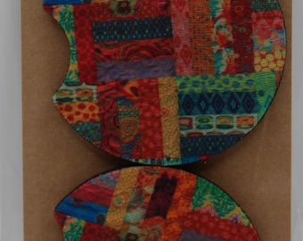 Puede incluir: Dos posavasos de coche coloridos con un diseño de patchwork. Los posavasos son redondos y tienen un recorte para una taza. El texto "Car Coasters Handmade with love" está impreso en la tarjeta marrón.