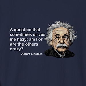 May include: A navy blue t-shirt with a white quote from Albert Einstein: "A question that sometimes drives me hazy: am I or are the others crazy?"  The quote is centered on the shirt with a cartoon image of Einstein to the right of the quote.
