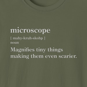 May include: A green t-shirt with a white graphic that says "microscope" and defines the word as "magnifies tiny things making them even scarier."