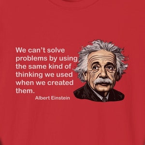 Könnte beinhalten: Rotes T-Shirt mit einem weißen Zitat von Albert Einstein: "Wir können Probleme nicht lösen, indem wir die gleiche Art von Denken verwenden, die wir verwendet haben, als wir sie geschaffen haben."