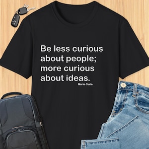 May include: Black t-shirt with white text that reads "Be less curious about people; more curious about ideas."  The text is attributed to Marie Curie.