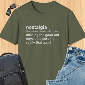 May include: A green t-shirt with a white graphic print that says "nostalgia" and defines the word as "missing the good old days that weren't really that good".