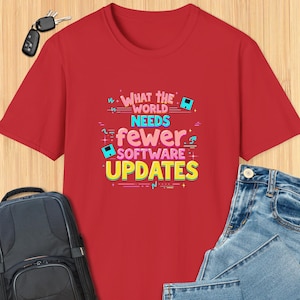 May include: Red t-shirt with a graphic design that says "What the world needs is fewer software updates". The graphic is in a retro style with colorful fonts and symbols.
