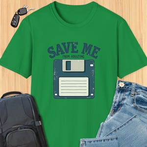 May include: Green t-shirt featuring the text "SAVE ME FROM ADULTING" and a retro floppy disk graphic.