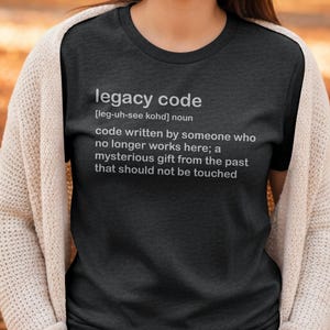 May include: A dark grey t-shirt with the definition of "legacy code" printed in white. The definition includes the pronunciation, and describes code written by someone who no longer works there, a mysterious gift from the past that should not be touched.