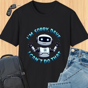 以下が含まれることがあります： 黒いTシャツに白いロボットのグラフィックと「申し訳ありません、デイブ。それはできません。」というテキストが書かれています