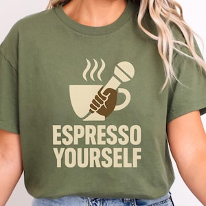 May include: Khaki green t-shirt with a coffee-themed graphic. The design features a coffee cup with steam, a hand holding a microphone, and the text "ESPRESSO YOURSELF" in a light brown colour.