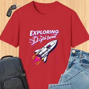 May include: Red t-shirt with the text "EXPLORING the Digital Cosmos" above a graphic of a white and silver rocket ship with yellow and pink flames. The shirt is paired with blue jeans, a black backpack, and keys.