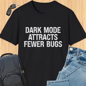 Pode incluir: Camiseta preta com texto branco que diz "DARK MODE ATTRACTS FEWER BUGS".