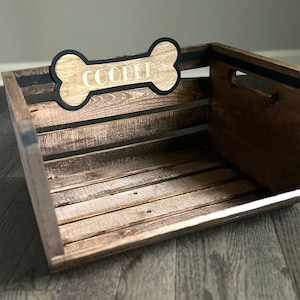 May include: A wooden dog bed with a black bone-shaped sign that says "COOPER" on it.