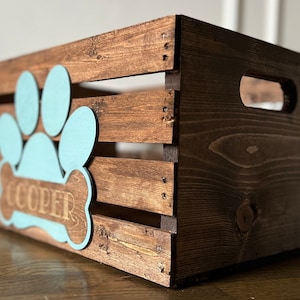 May include: A wooden crate with a blue paw print and bone design. The bone has the name "COOPER" engraved on it.