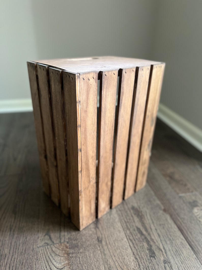 May include: A wooden crate with a natural brown finish. The crate is made of slats of wood and has a rectangular shape.