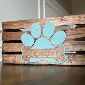 May include: A wooden crate with a blue paw print and bone design. The bone has the name "COOPER" written on it.
