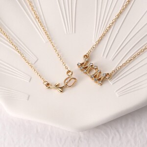 May include: Two gold necklaces with a rose pendant and a MOM pendant with rhinestones.