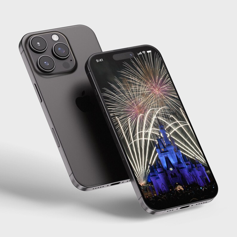May include: A black iPhone with a fireworks display over a castle on the screen. The time on the screen is 9:41.