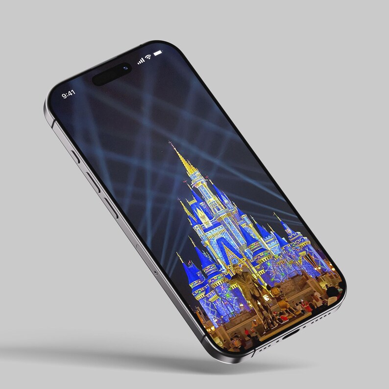 May include: A smartphone displaying a nighttime image of Cinderella's Castle at Walt Disney World. The castle is illuminated with blue and gold lights, and there are fireworks in the background.