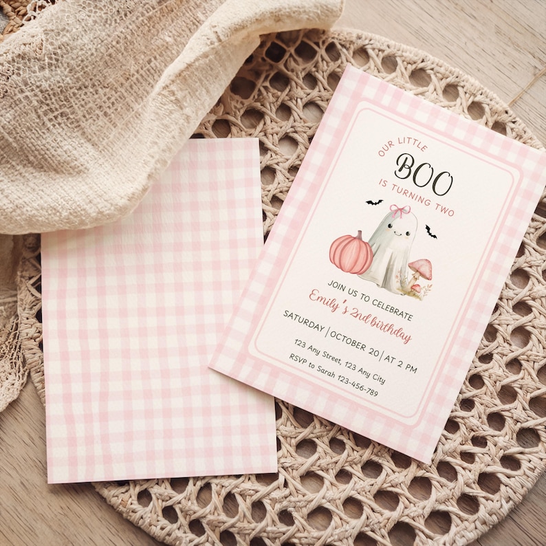 May include: Pink gingham-patterned birthday invitation with the text "OUR LITTLE BOO IS TURNING TWO." The invitation features a ghost, pumpkin, and mushroom illustration. Includes event details: date, time, and RSVP information.