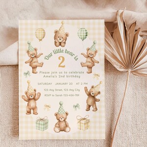 Puede incluir: Una invitación de cumpleaños con un fondo de cuadros vichy amarillo claro. La invitación presenta ilustraciones de osos de peluche con sombreros de fiesta y globos. El texto dice "Our little bear is 2" y los detalles del segundo cumpleaños de Amelia.
