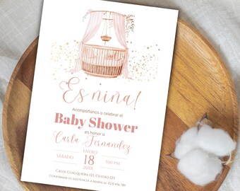 Può includere: Un invito a un baby shower rosa e oro con un'illustrazione ad acquerello di una culla con baldacchino e un mobile. Il testo recita "Es nina!" e "Baby Shower in onore di Carla Fernandez".