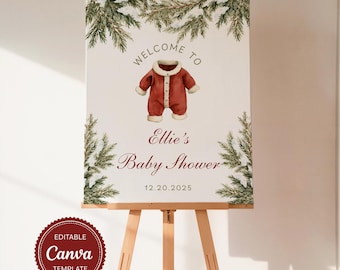 May include: A baby shower welcome sign on an easel. The sign features a watercolor illustration of a red onesie and text that reads "Welcome to Ellie's Baby Shower" and the date 12.20.2025. The sign has a Canva template logo.