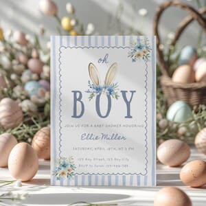 Op de afbeelding: Een uitnodiging voor een babyshower met een blauw-witte gestreepte rand. De uitnodiging luidt "oh BOY" met konijnenoren en bloemaccenten. Details zijn de naam van de geëerde, datum, tijd en RSVP-informatie. Paaseieren en een mand zijn op de achtergrond.