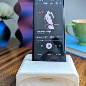 Phone stand with acoustic booster. Comes in a variety of colors and may be customized for the dimensions of any device.