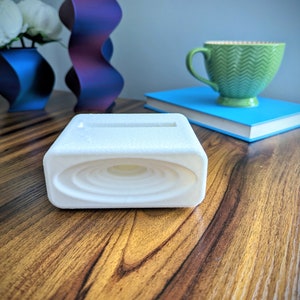 Phone stand with acoustic booster. Comes in a variety of colors and may be customized for the dimensions of any device.