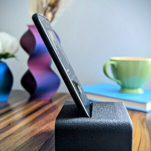 Phone stand with acoustic booster. Comes in a variety of colors and may be customized for the dimensions of any device.