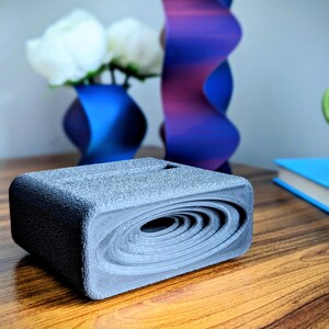 Phone stand with acoustic booster. Comes in a variety of colors and may be customized for the dimensions of any device.
