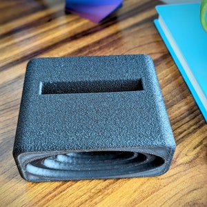 Phone stand with acoustic booster. Comes in a variety of colors and may be customized for the dimensions of any device.