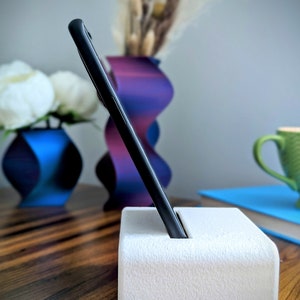 Phone stand with acoustic booster. Comes in a variety of colors and may be customized for the dimensions of any device.
